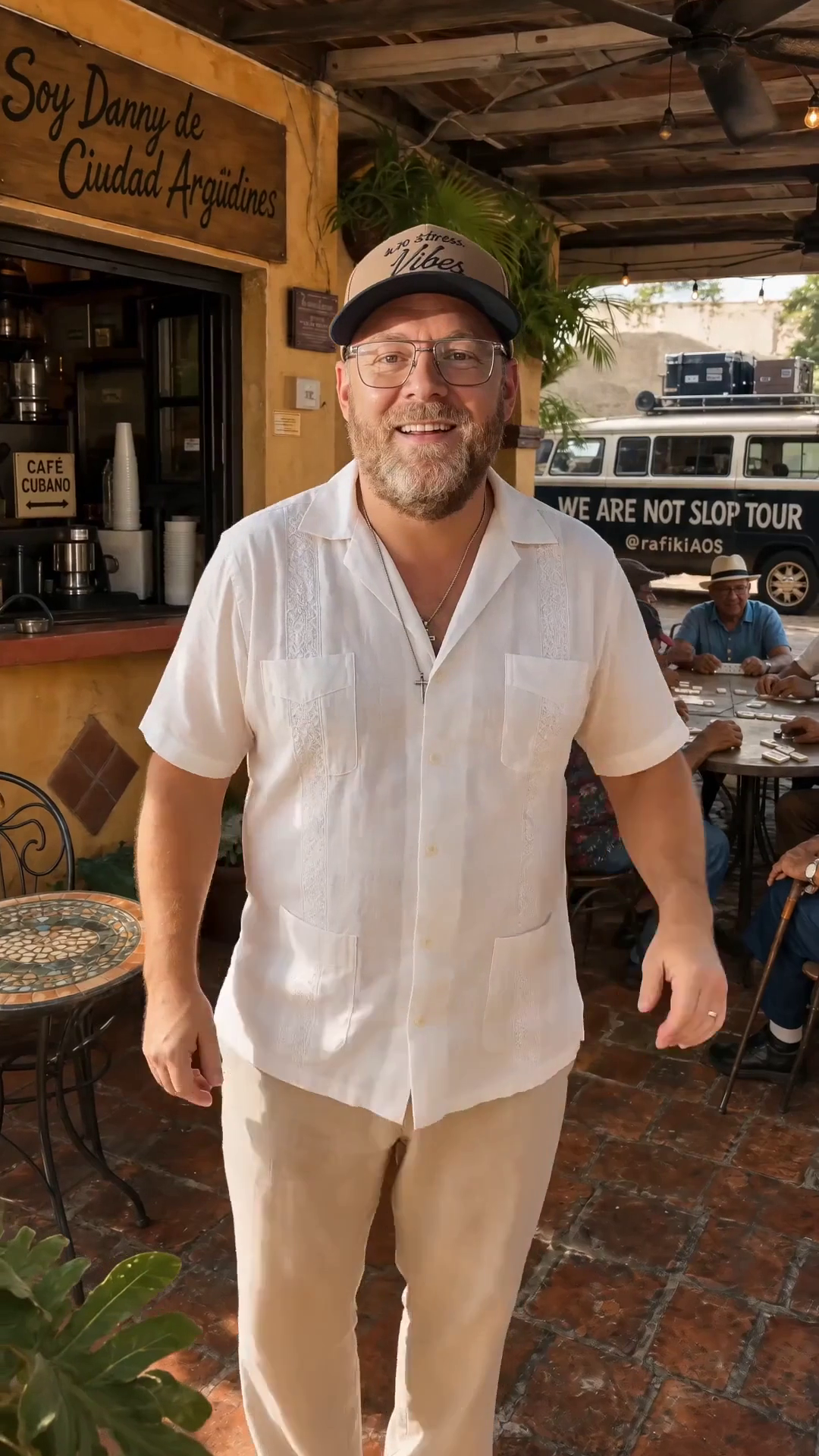 Danny’s likeness in a white shirt at an imagined Cuban café, with the tour van behind him.
